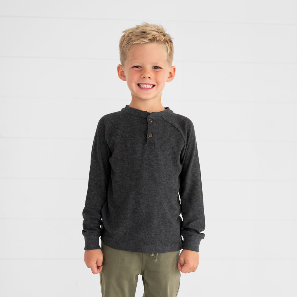 Close up image of a child wearing a Heather Black Waffle Henley Tee and Olive Denim Jogger