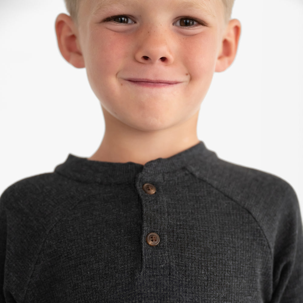 Close up image of a child wearing a Heather Black Waffle Henley Tee