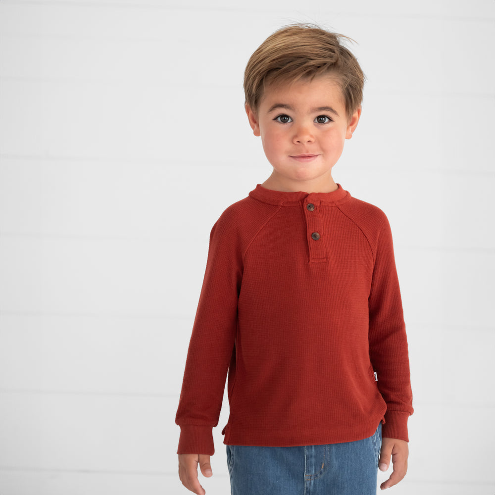 Close up image of a child wearing a Rust Waffle Henley Tee