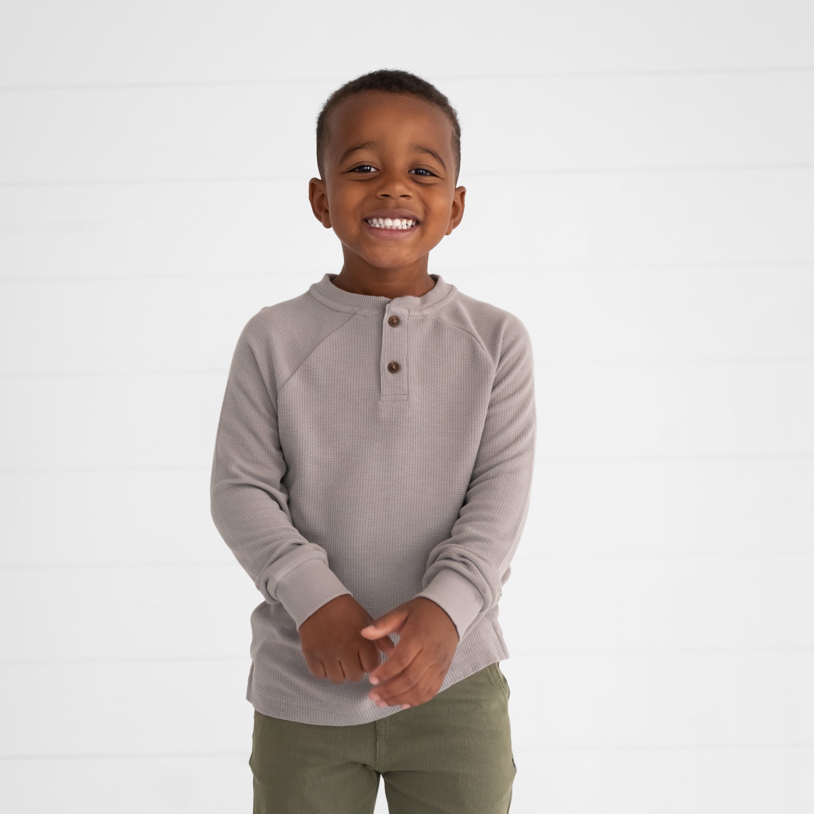 Close up image of a child wearing a Pebble Waffle Henley Tee and Olive Denim Jogger