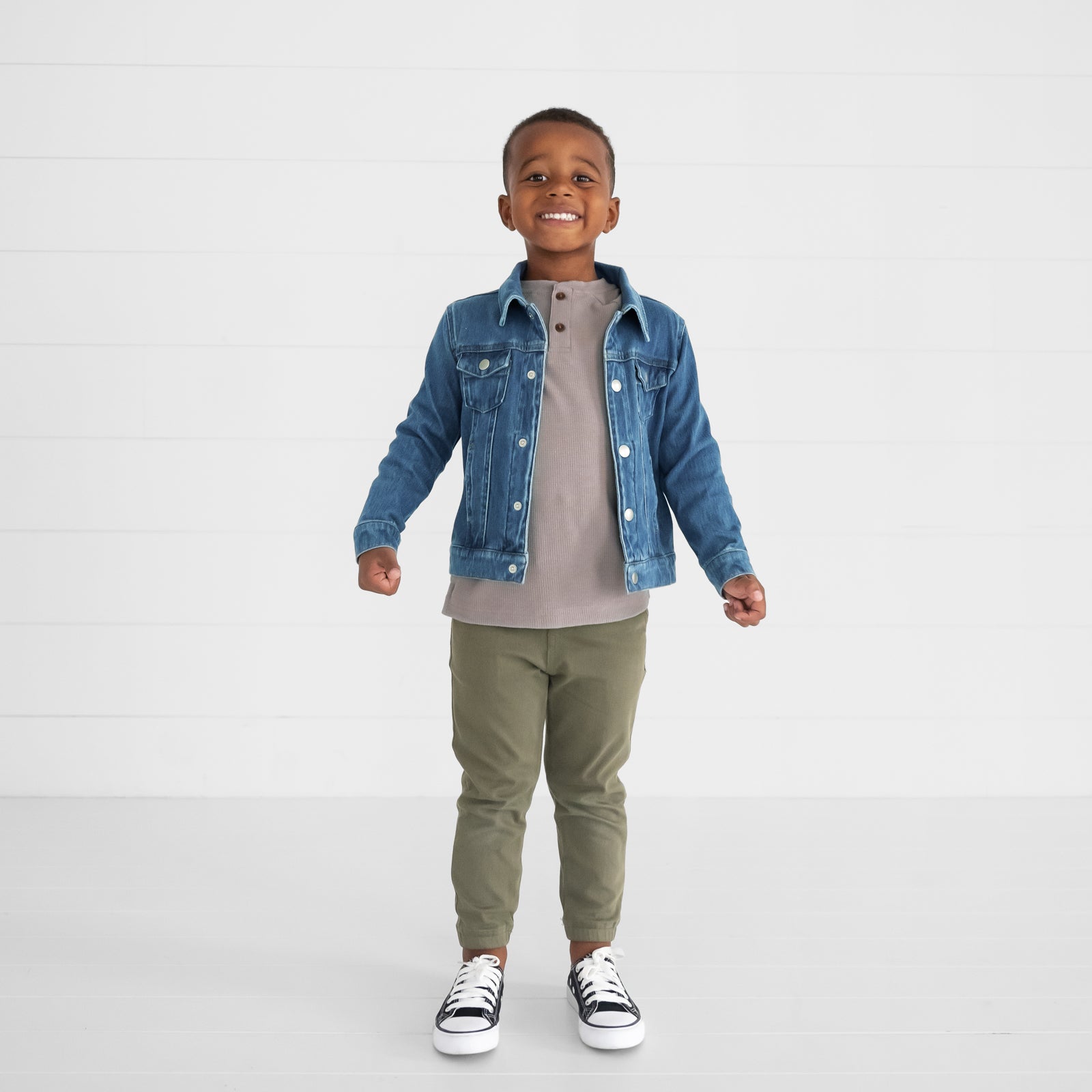 Image of a child wearing a Pebble Waffle Henley Tee, Midwash Blue Denim Trucker Jacket, and Olive Denim Joggers