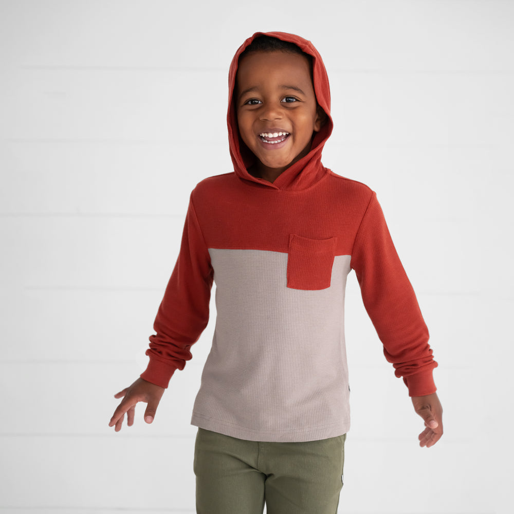 Close up image of a child wearing a Rust Waffle Hooded Tee with the hood up