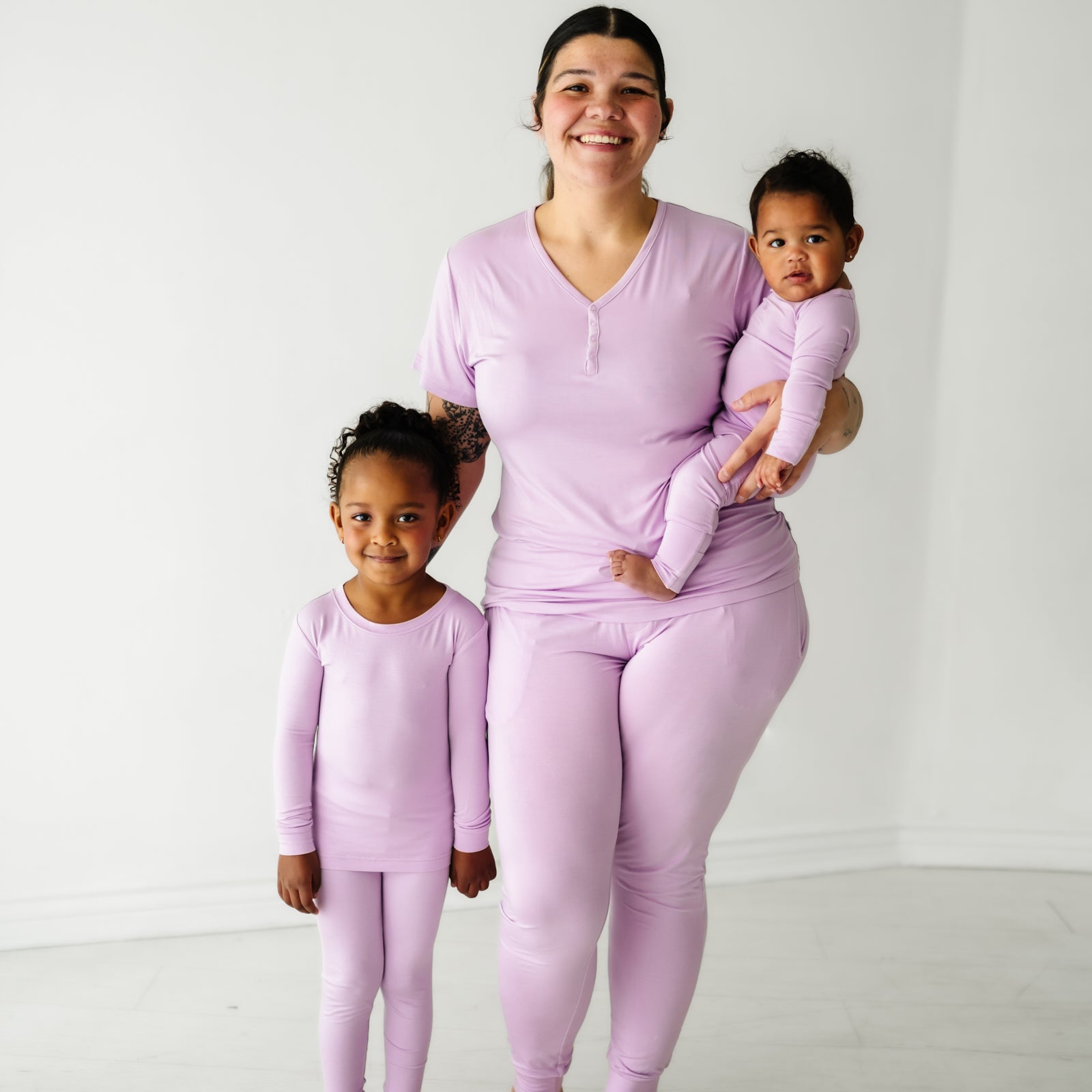 Family of three wearing matching Light Orchard pajama sets. mom is wearing women's Light Orchard women's pajama top and matching women's pj pants. Kids are wearing matching Light Orchard two piece and zippy styles 