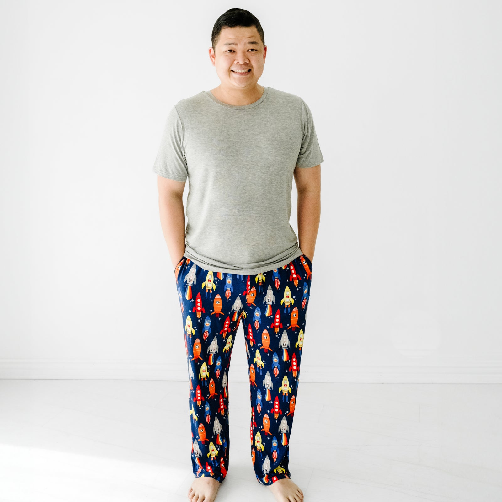 Man wearing men's Navy Space Explorer pajama pants paired with a solid heather gray men's pajama top