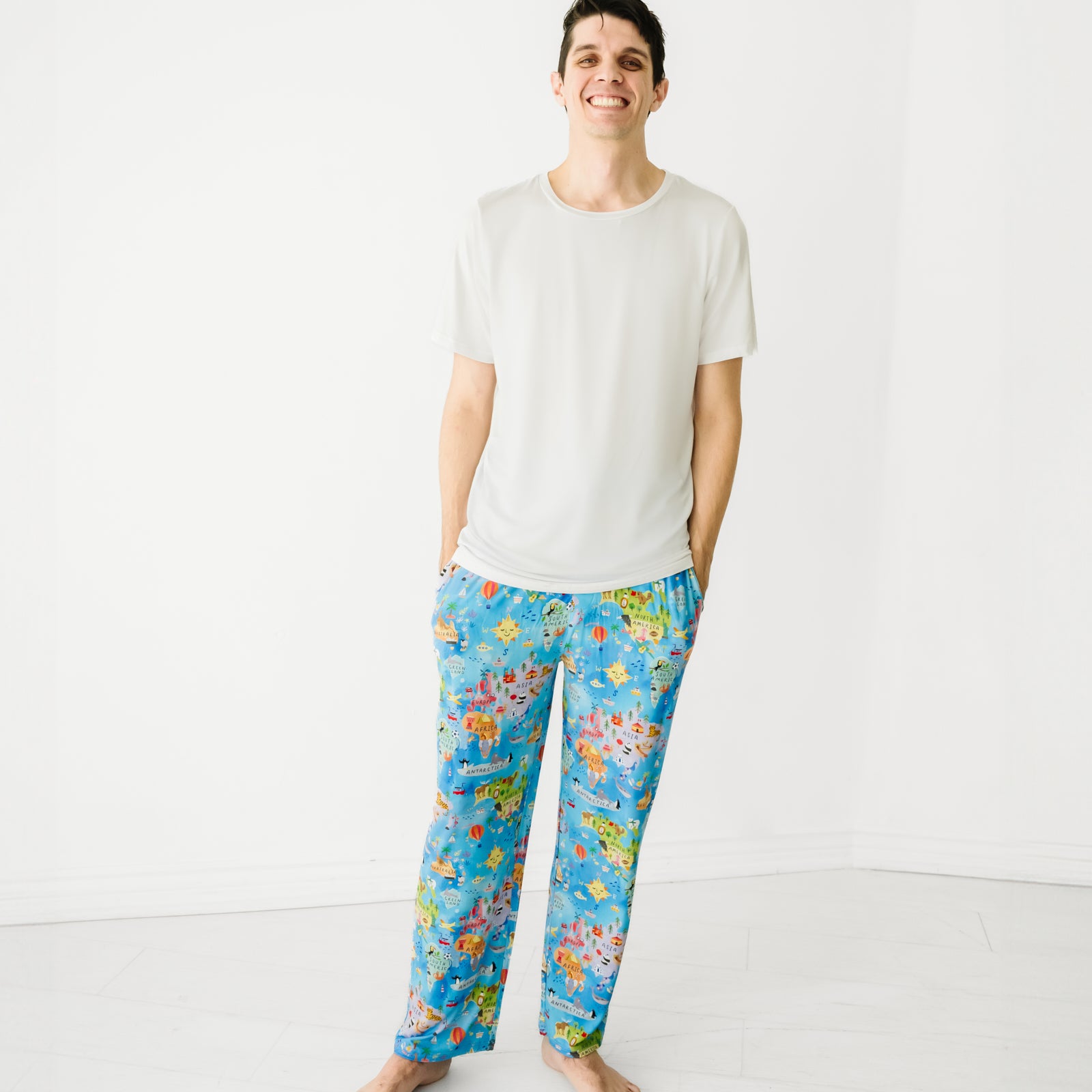 Man wearing a Bright White Men's Short Sleeve Pajama Top and coordinating Around The World printed men's pajama pants