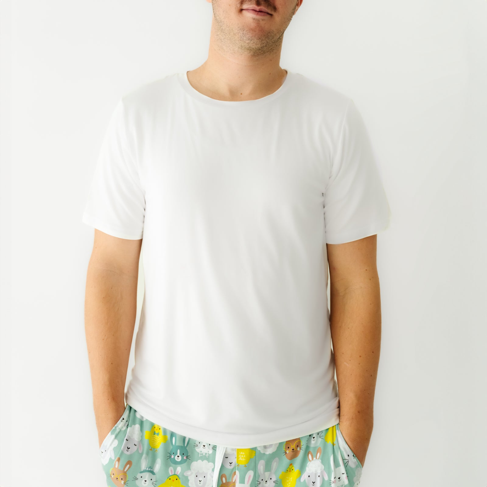 Close up image of a man wearing Aqua Pastel Parade men's pajama pants paired with a Bright White men's short sleeve pajama top