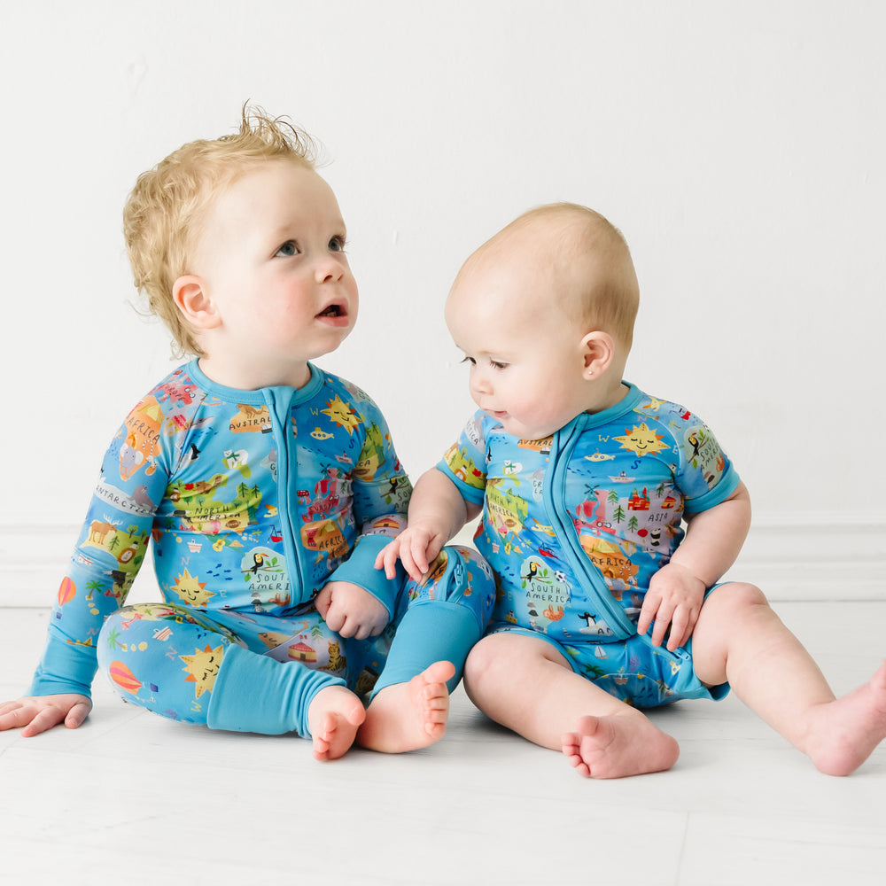 Two children sitting together wearing matching Around the World zippies in standard and shorty styles