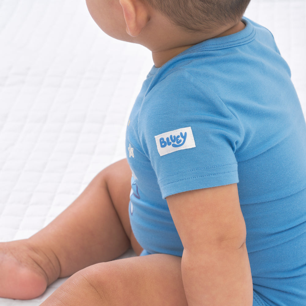 Close up side view image of a child wearing a Bluey graphic bodysuit