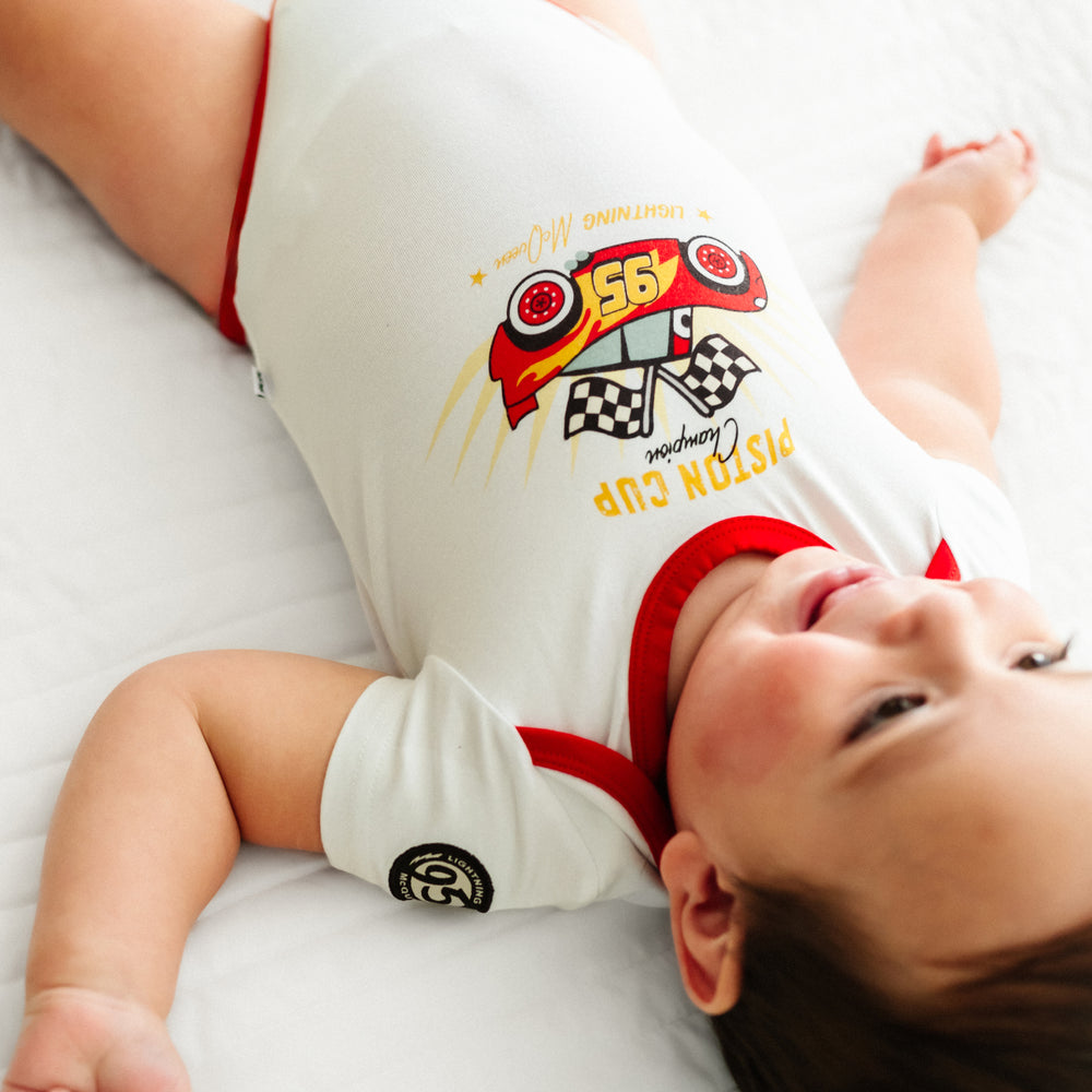 Close up image of a child laying on a blanket wearing a Lightning McQueen graphic bodysuit