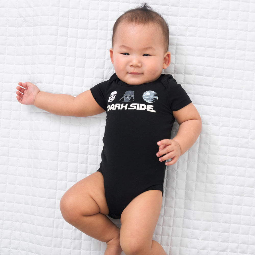 Child laying on a blanket wearing a Dark Side graphic bodysuit