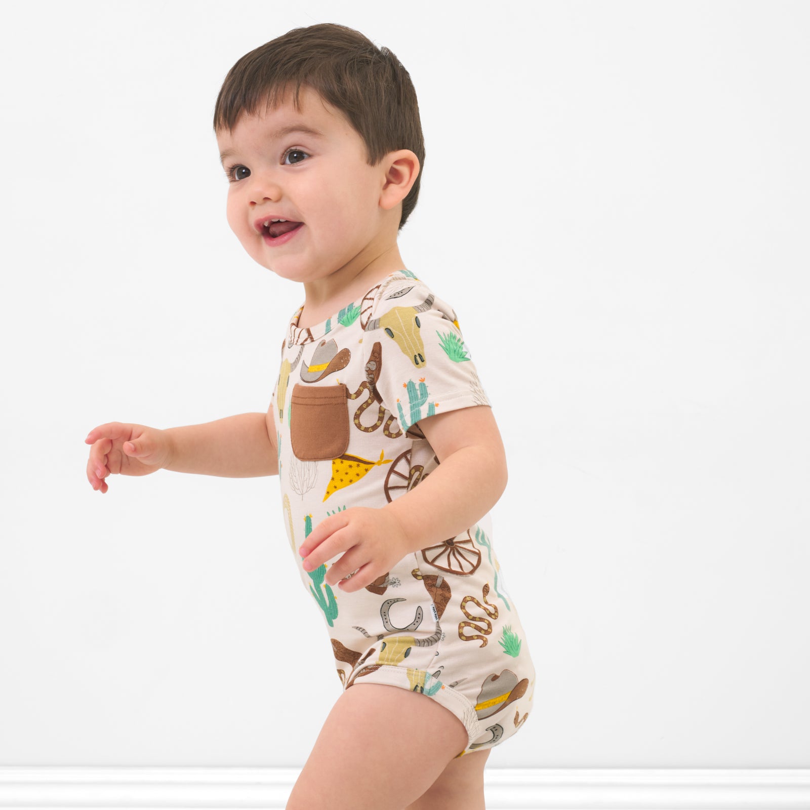 Side view of a child wearing a Caramel Ready to Rodeo Pocket Bodysuit