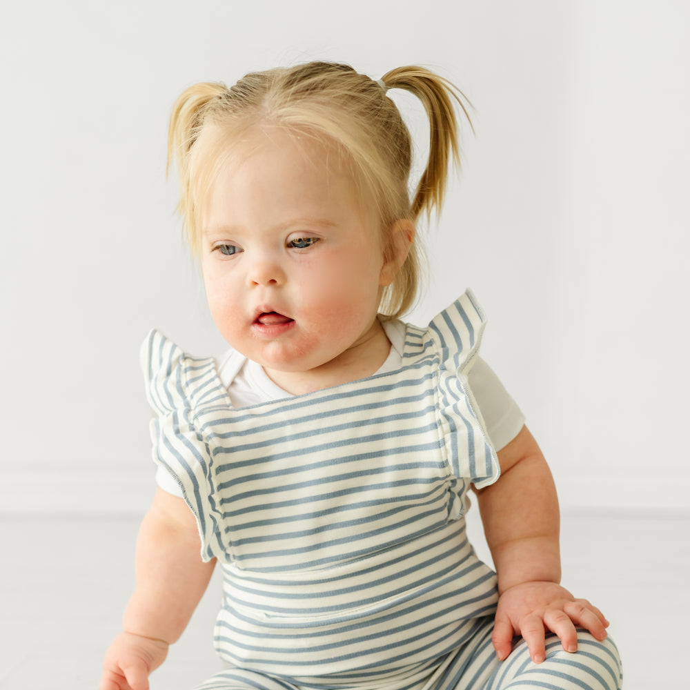 Close up image of a child wearing Fog Stripes ruffle overall and coordinating Play bodysuit