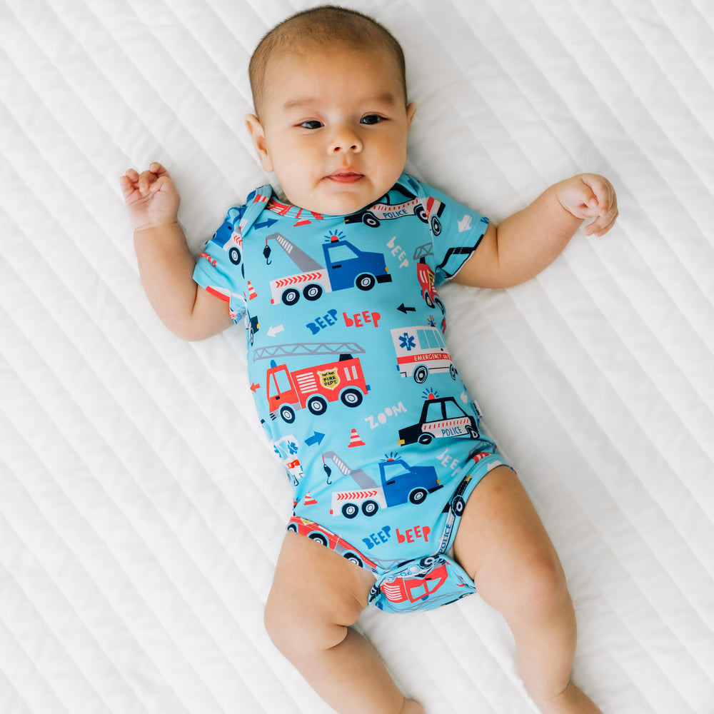 Child laying on a bed wearing a To The Rescue Bodysuit