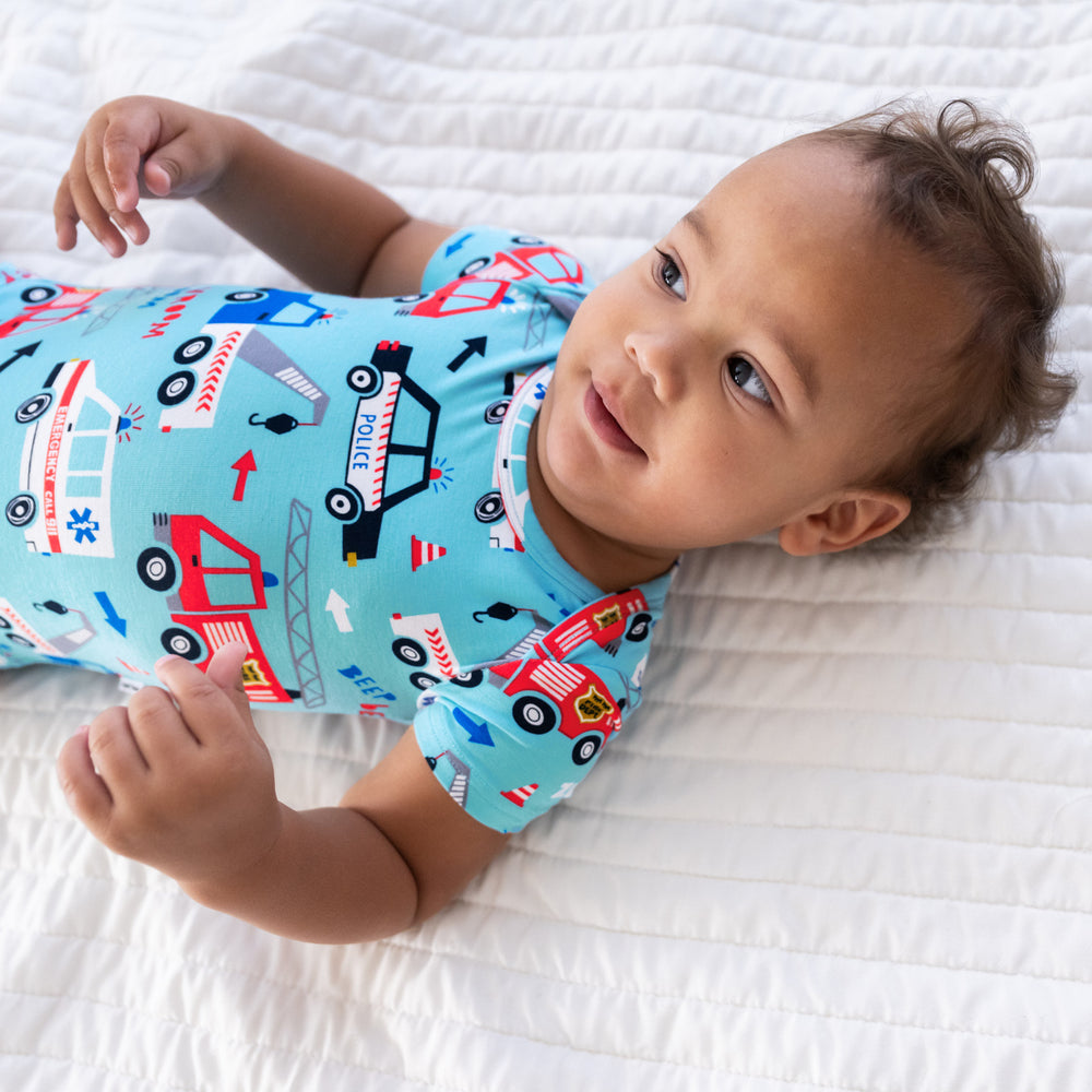 Top view close up image of baby laying down wearing the To The Rescue Bodysuit and displaying the should details