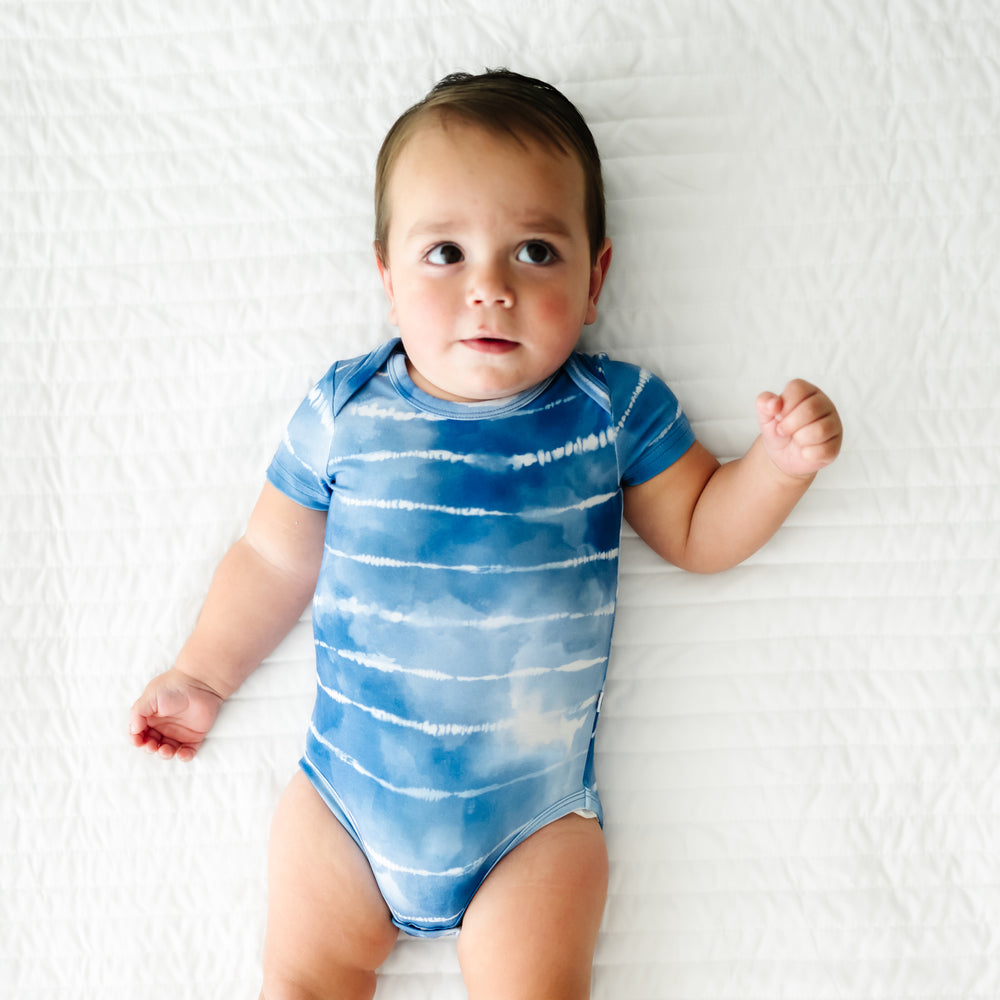 Child laying on a blanket wearing a Blue Tie Dye Dreams bodysuit