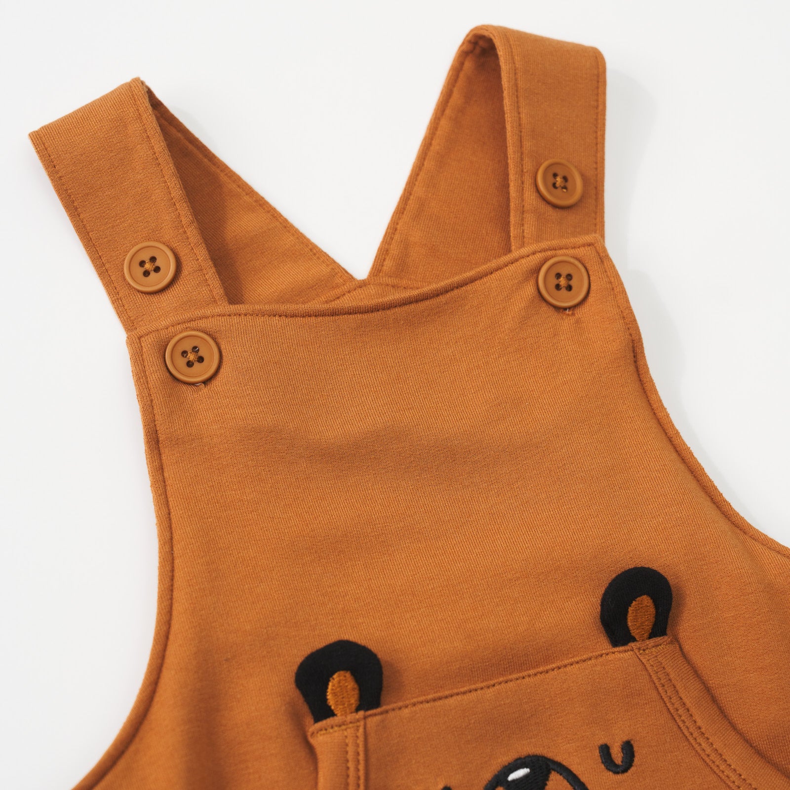 Close-up view of the button straps on a Golden Brown graphic overall