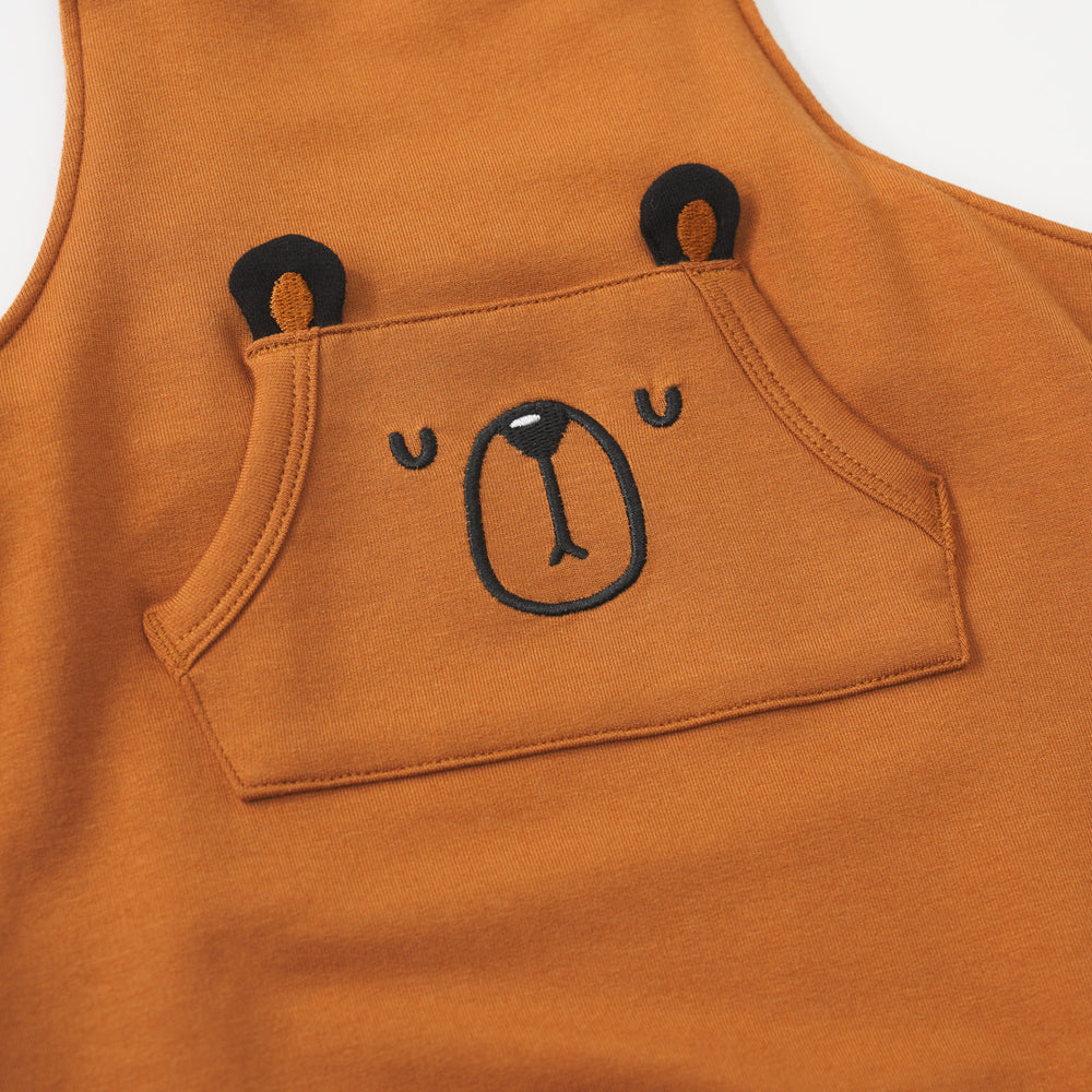 Close-up view of the front pocket with bear design on a Golden Brown graphic overall