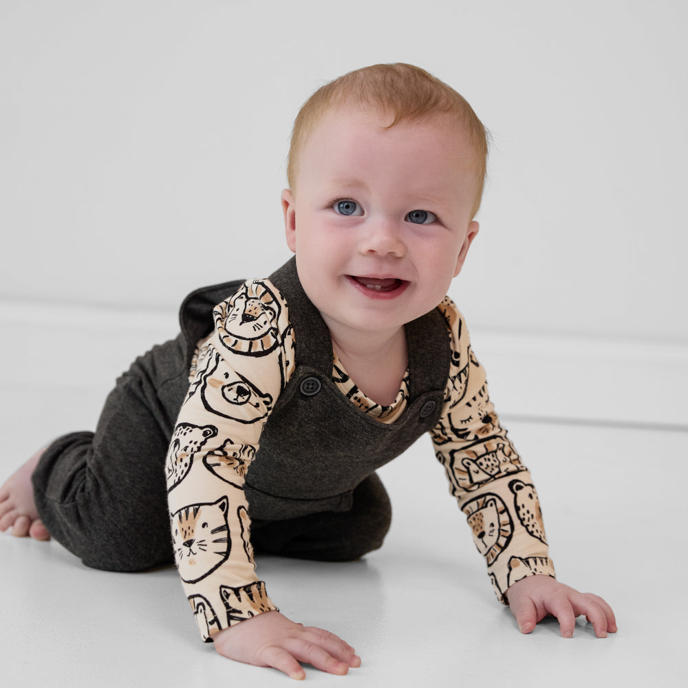 Child crawling wearing a Heather Black overall paired with a tan animal print long sleeve baby bodysuit