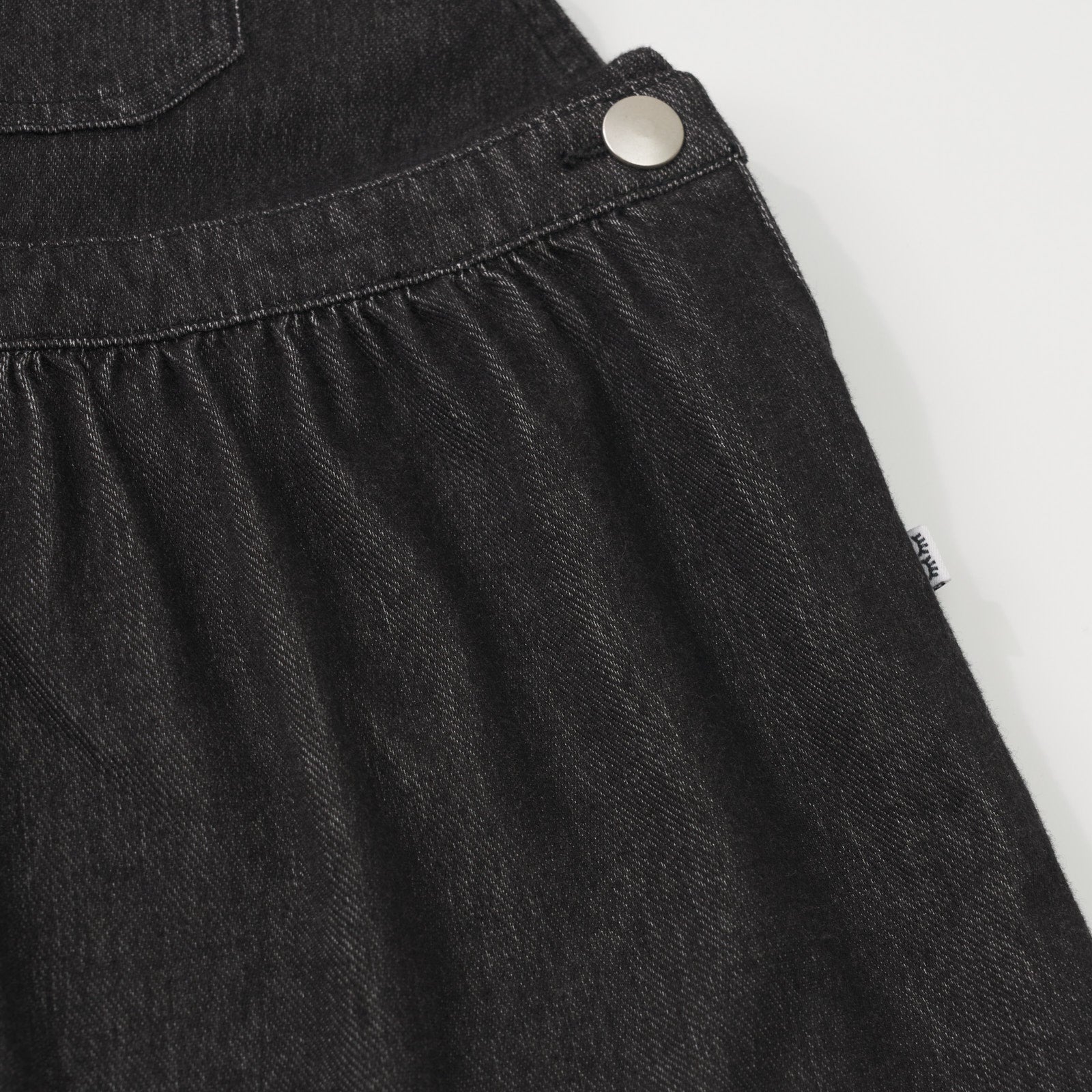 Close up view of the skirt on a Black denim tank skirt overall