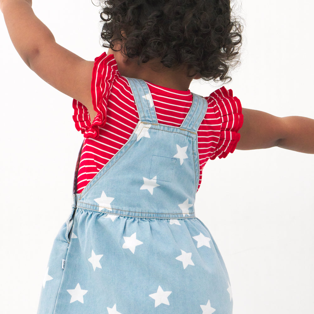 Back view image of a child wearing a Denim Stars tank skirt overall and coordinating Play bodysuit