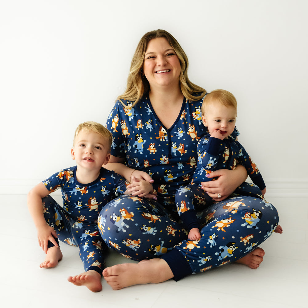Mother and her two children matching wearing Bluey Dance Mode pajamas. Mom is wearing women's Bluey Dance Mode women's pajama top and matching women's pajama pants. Children are matching wearing Bluey Dance Mode short sleeve two piece pajama set and zippy