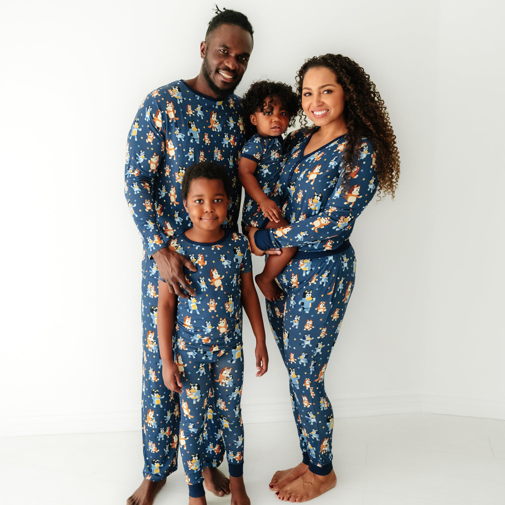 Family of four wearing matching Bluey Dance Mode pajama sets. Dad is wearing men's Bluey Dance Mode men's pajama top and matching men's pajama pants. Mom is wearing Women's Bluey Dance Mode women's pajama top and matching women's pajama pants. Their children are wearing matching pjs in two piece and zippy styles