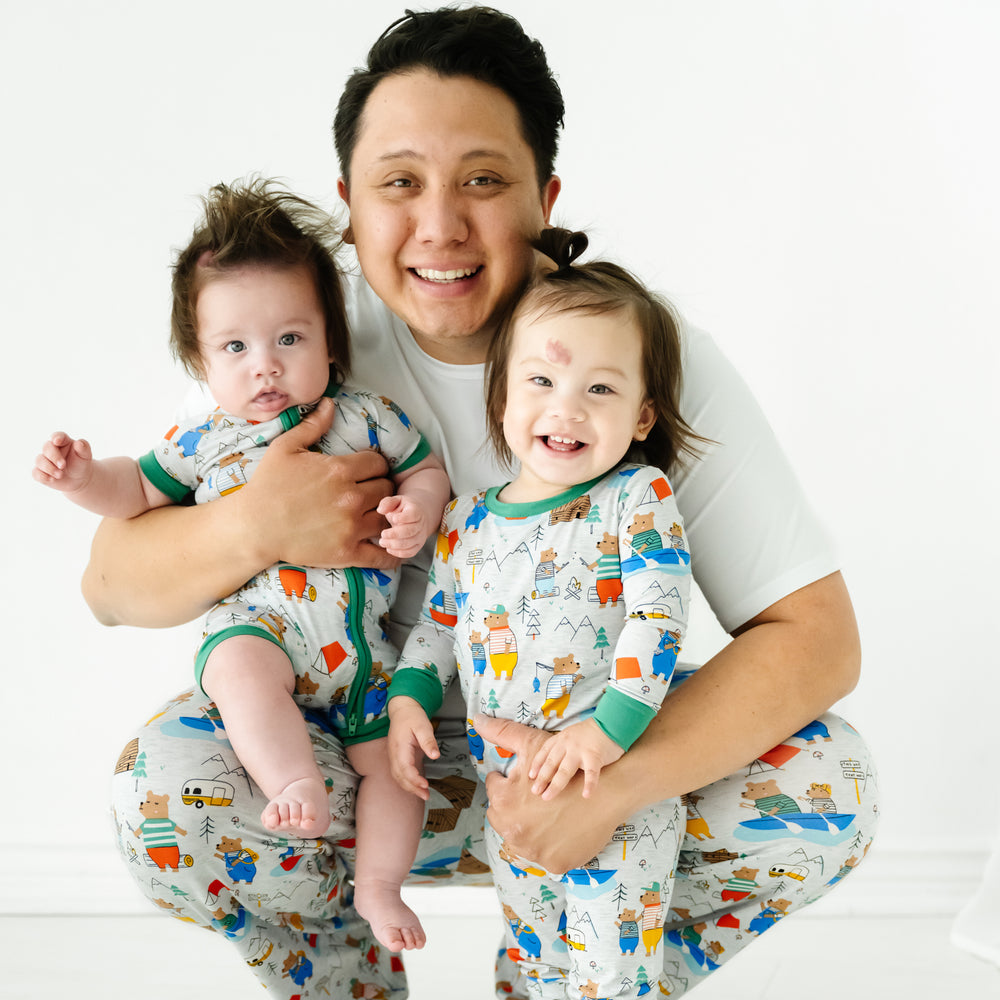 Dad holding his two childrend wearing matching Papa Bear pajamas. Dad is wearing men's Papa Bear pajama pants and a men's Bright White pj top. His children are wearing matching Papa Bear pjs in Shorty Zippy and two piece styles