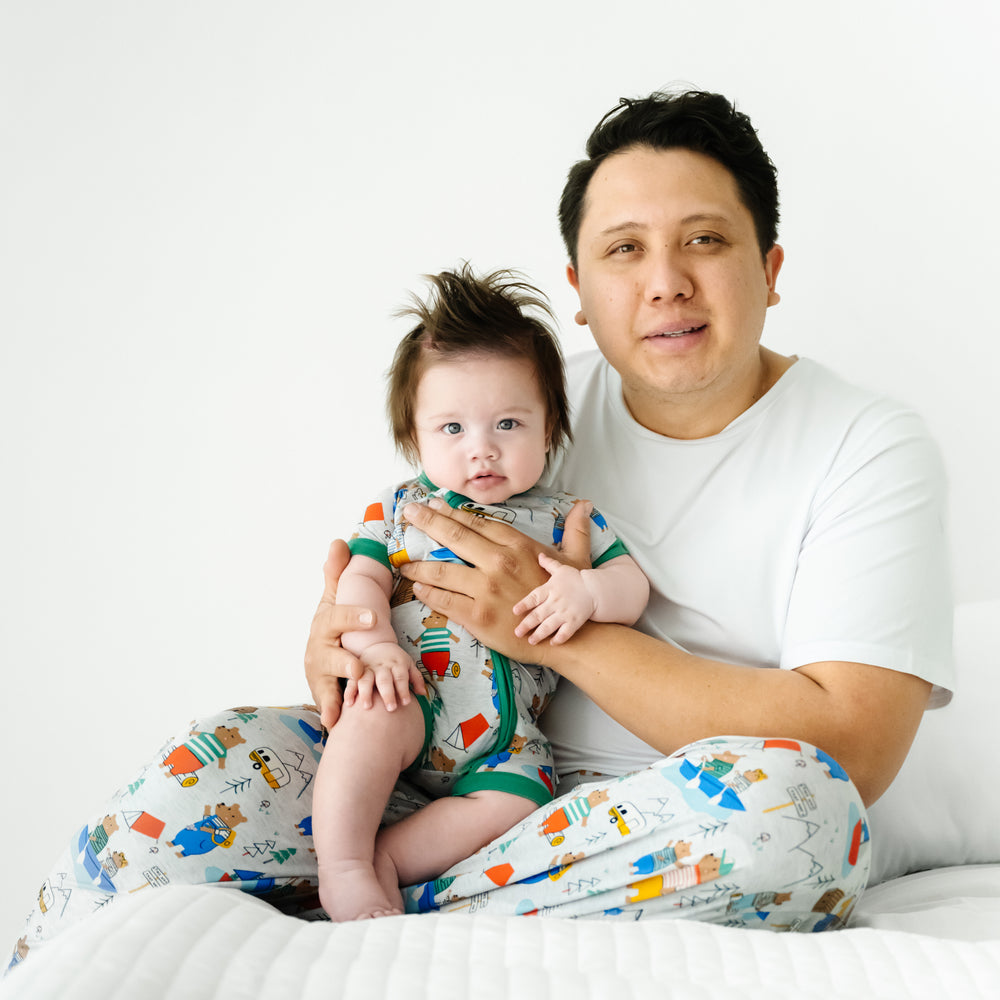 Dad holding his child wearing matching Papa Bear pajamas. Dad is wearing men's Papa Bear pajama pants and a men's Bright White pj top. Child is wearing a matching Papa Bear Zippy