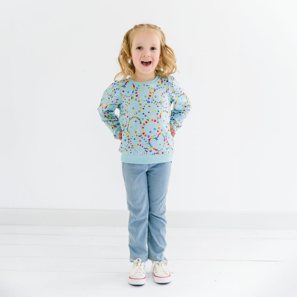 Child standing wearing a Friends Forever Puff Sleeve Crewneck and denim jeggings