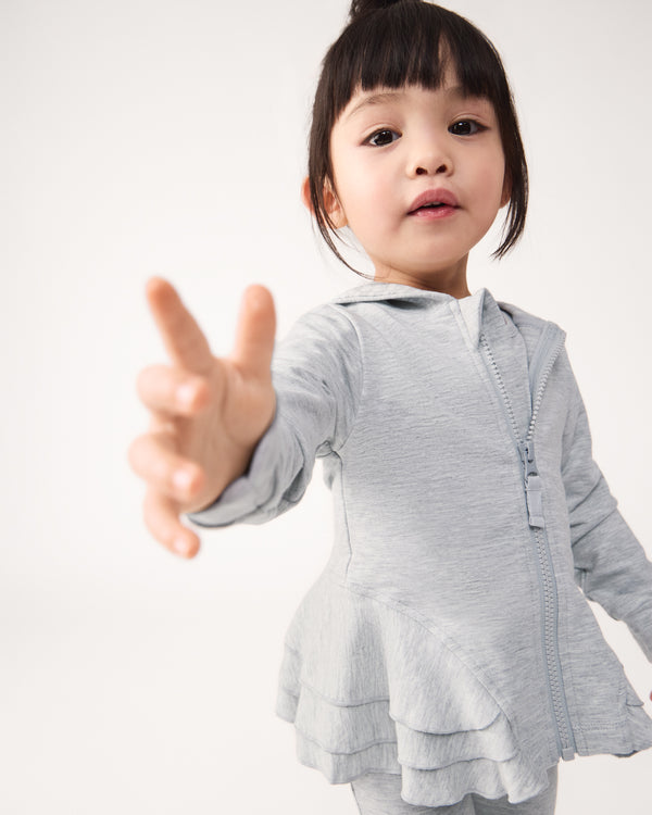 Girl reaching for the camera wearing the Light Heather Gray Peplum Hoodie