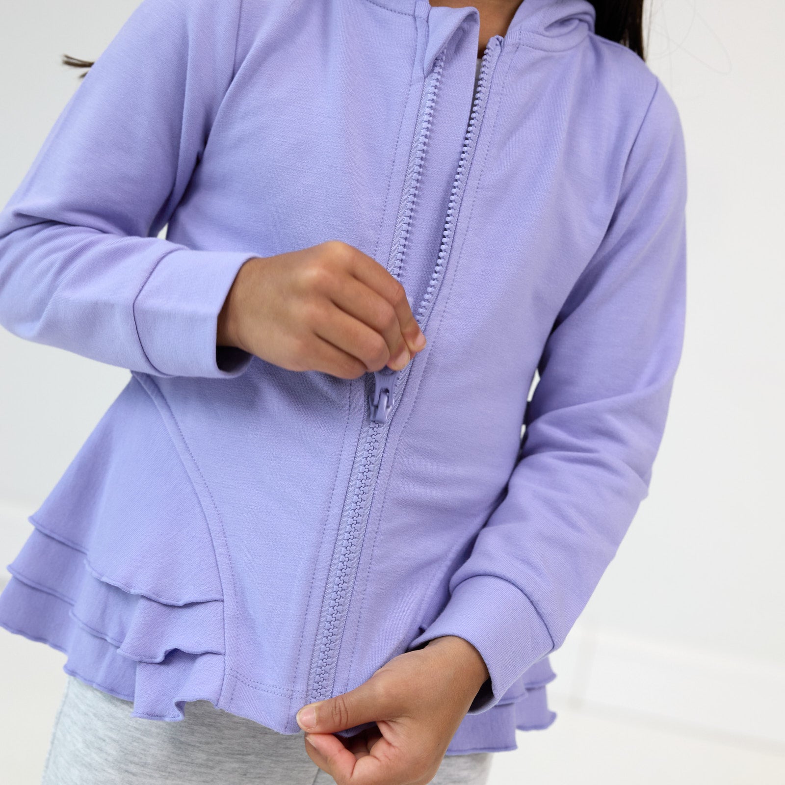 Close up image of the peplum and zipper details on the Light Iris Peplum Hoodie