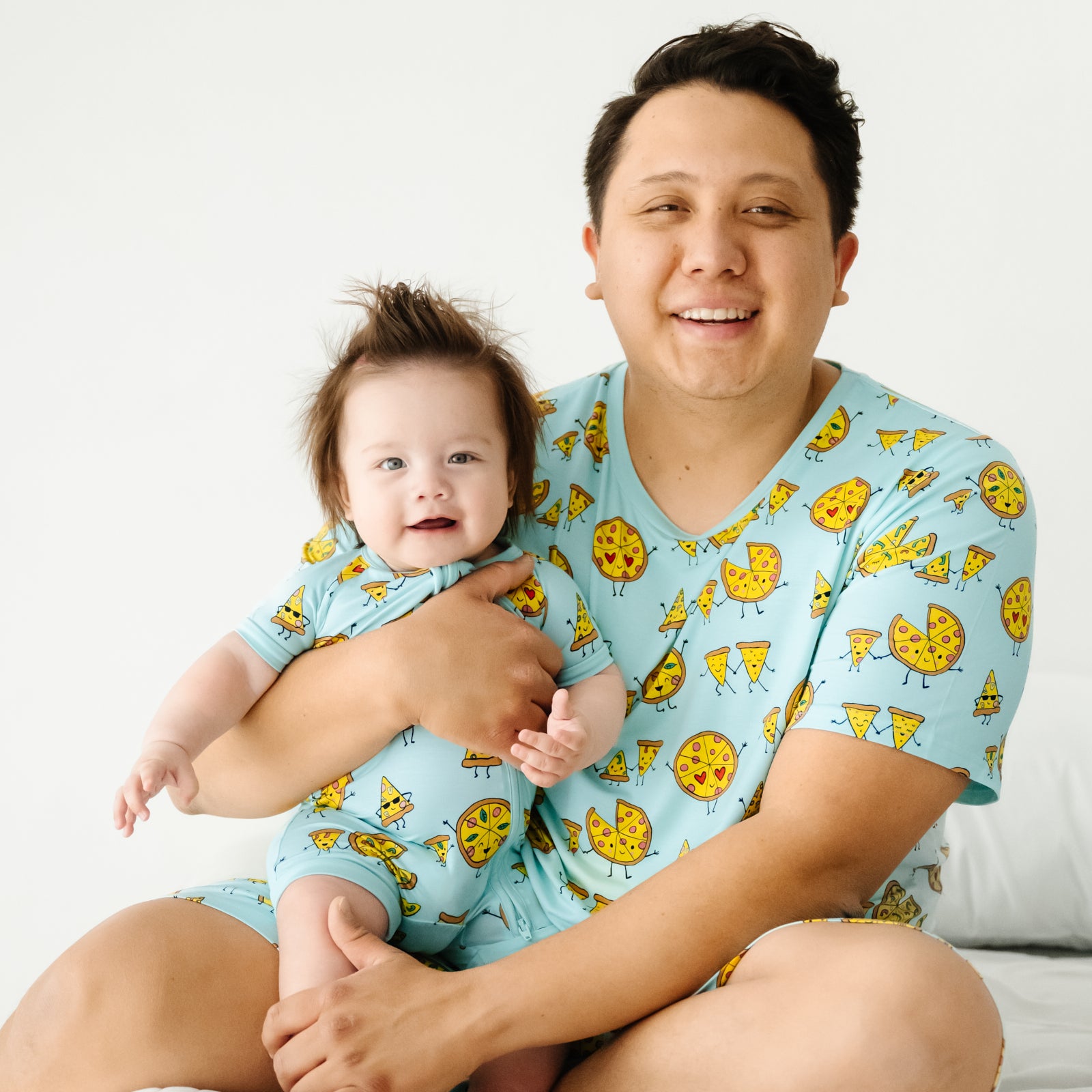 Father and child wearing matching Pizza Pals pajamas. Dad is wearing men's Pizza Pals pj top and child is wearing a matching shorty zippy