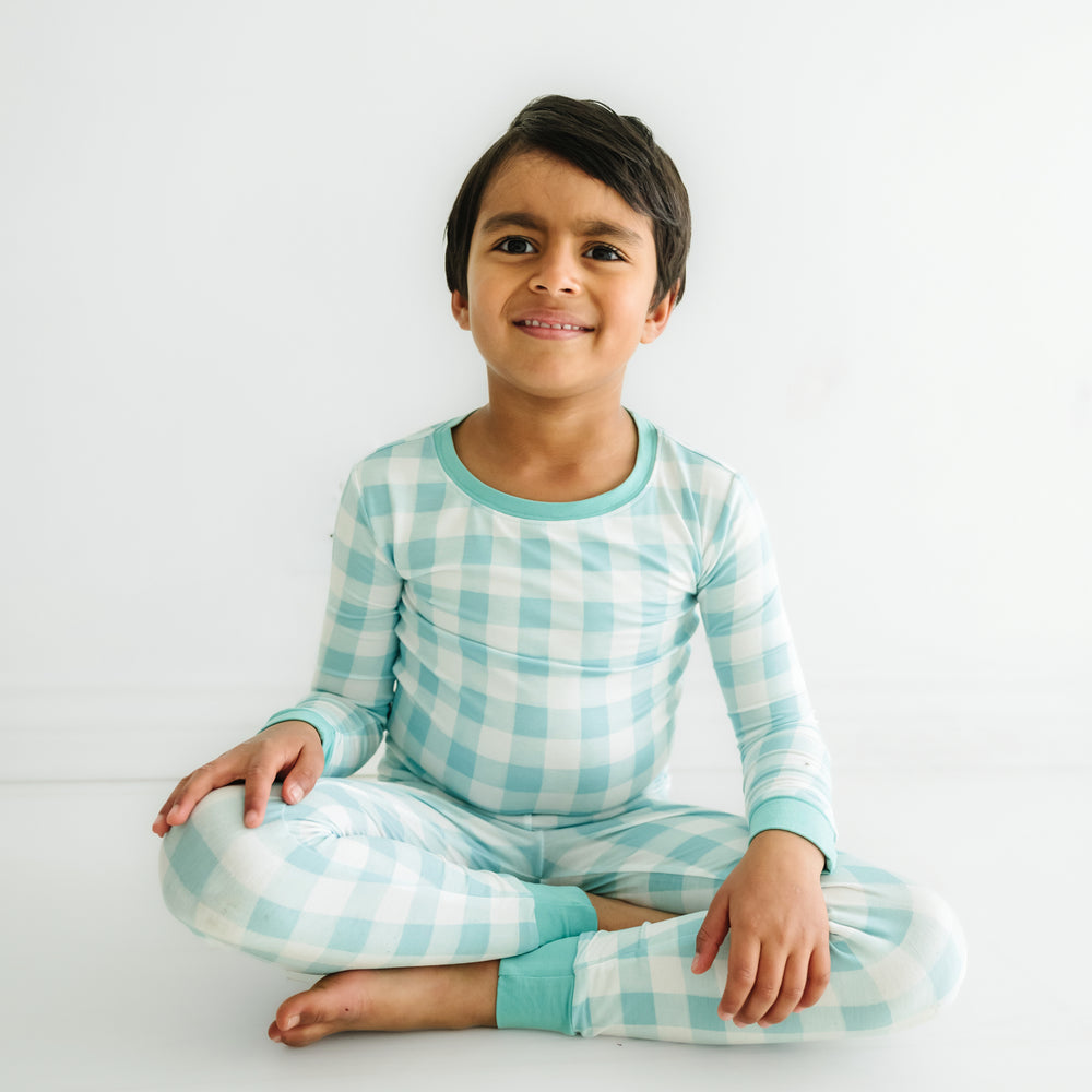 Click to see full screen - child sitting wearing an Aqua Gingham two piece pajama set