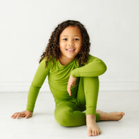 Child sitting wearing an Avocado two piece pajama set