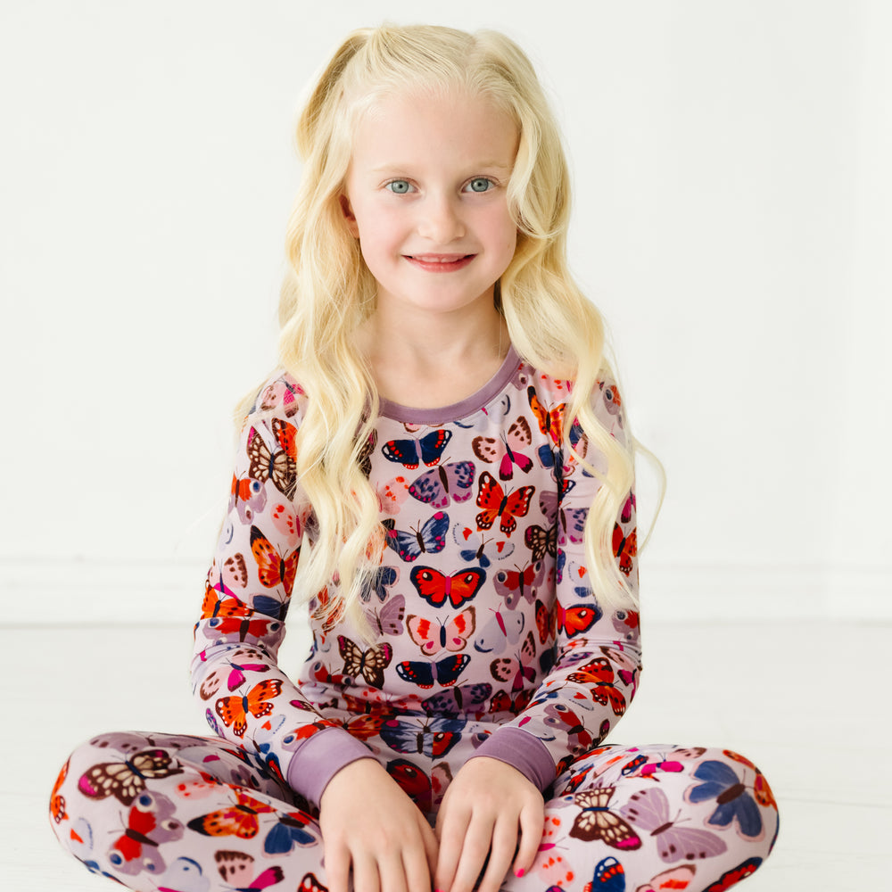 Child sitting on the ground wearing a Butterfly Kisses two-piece pajama set