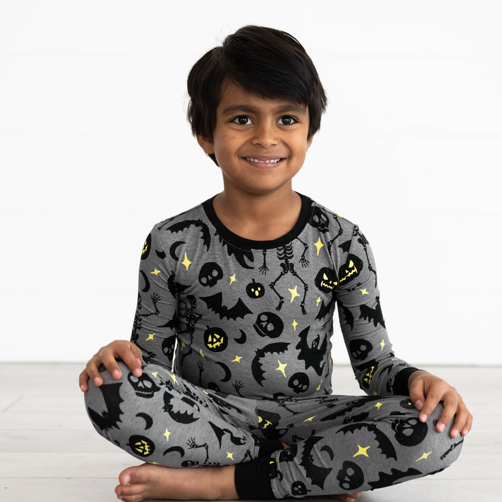 Boy sitting while in the Gray Glowing Ghouls Two-Piece Pajama Set