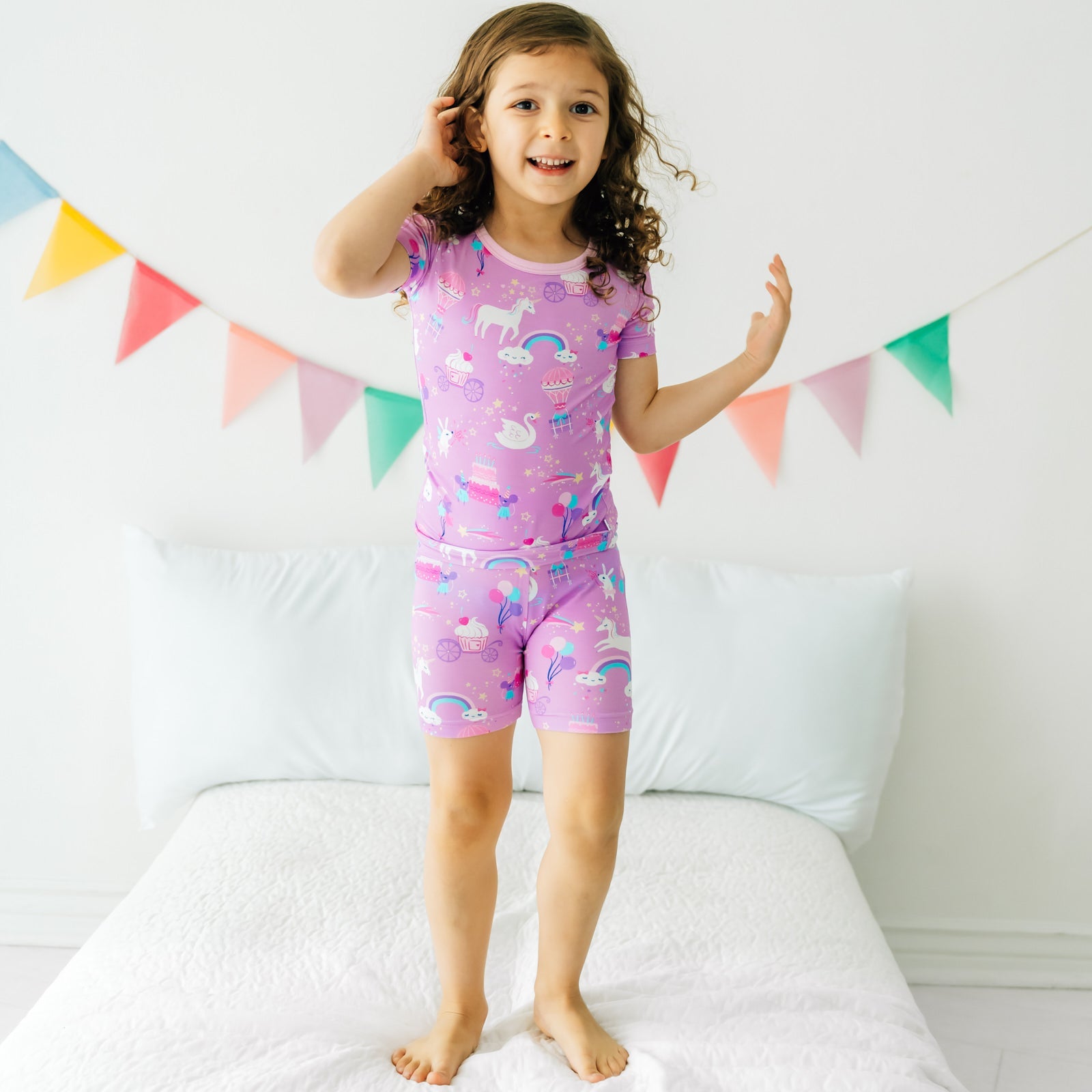 Child playing on a bed wearing a Magical Birthday two piece shorts and short sleeve pj set