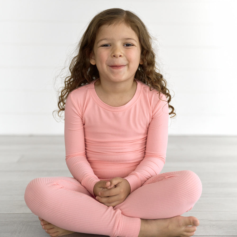 Girl sitting while wearing the Bubblegum Ribbed Two-Piece Pajama Set