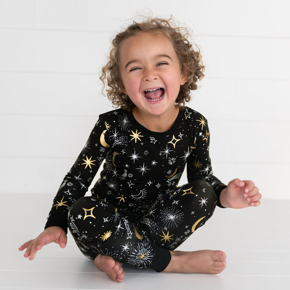 Child sitting and posing wearing a Celebration Stars two piece pj set