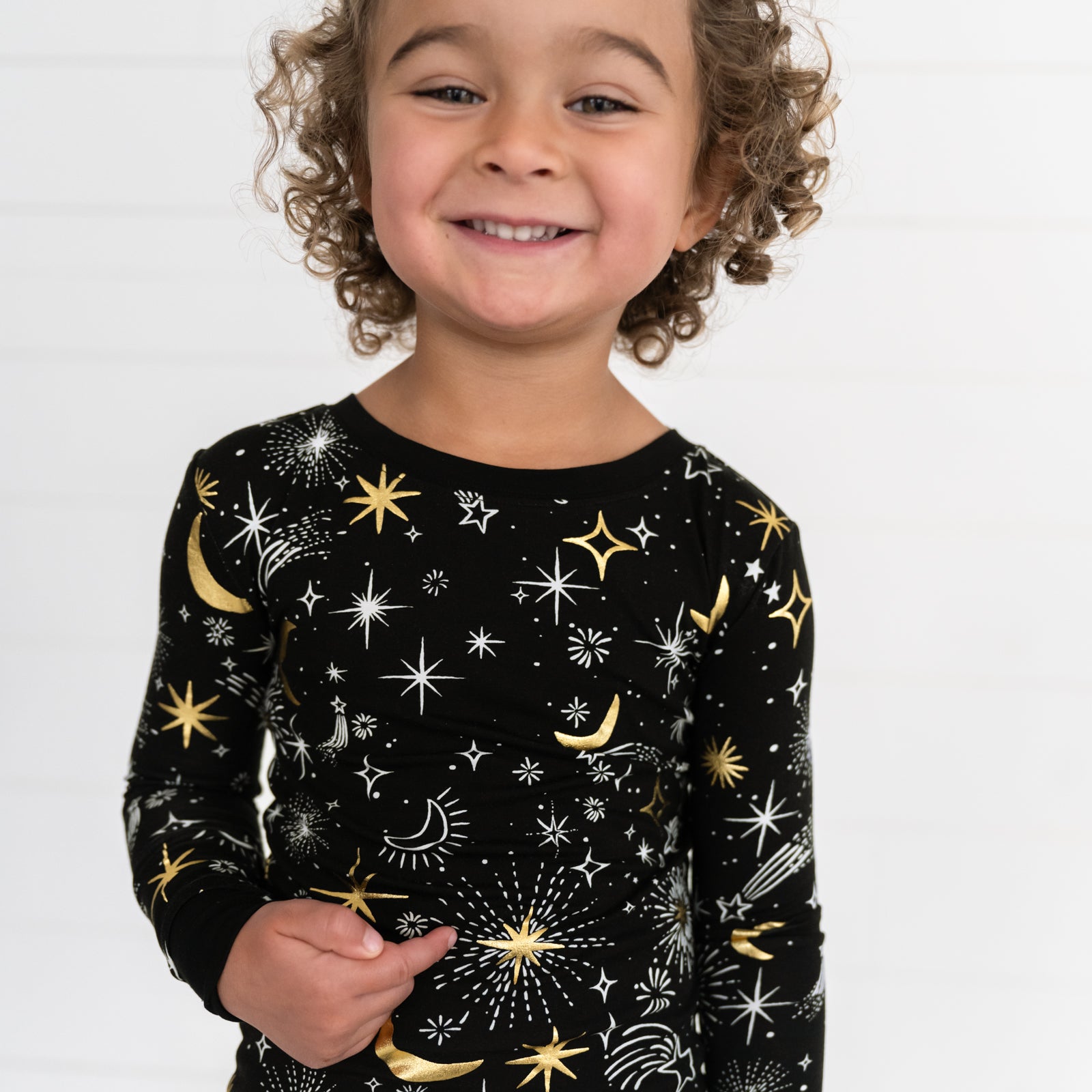 Image of a child wearing a Celebration Stars two piece pj set showing off the metallic stars