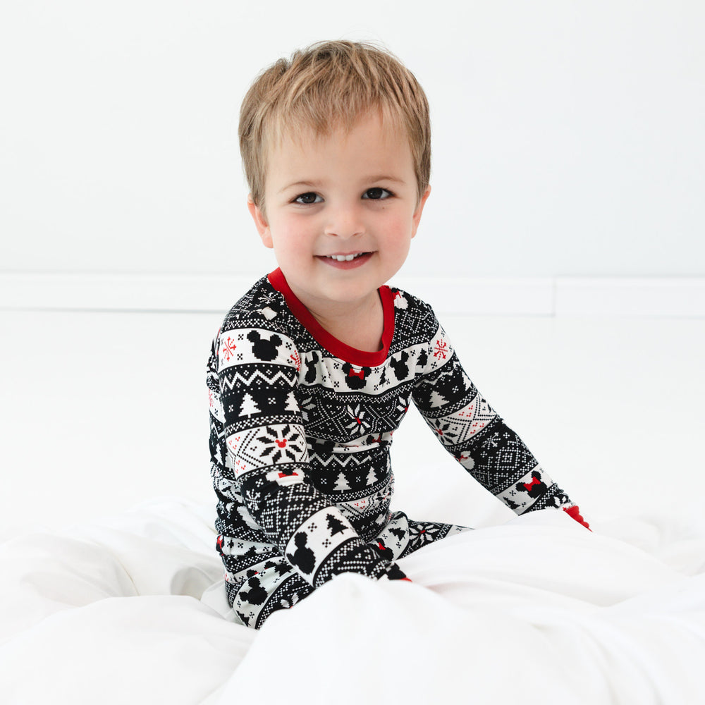 Child sitting on a bed wearing a Mickey Fair Isle two piece pj set