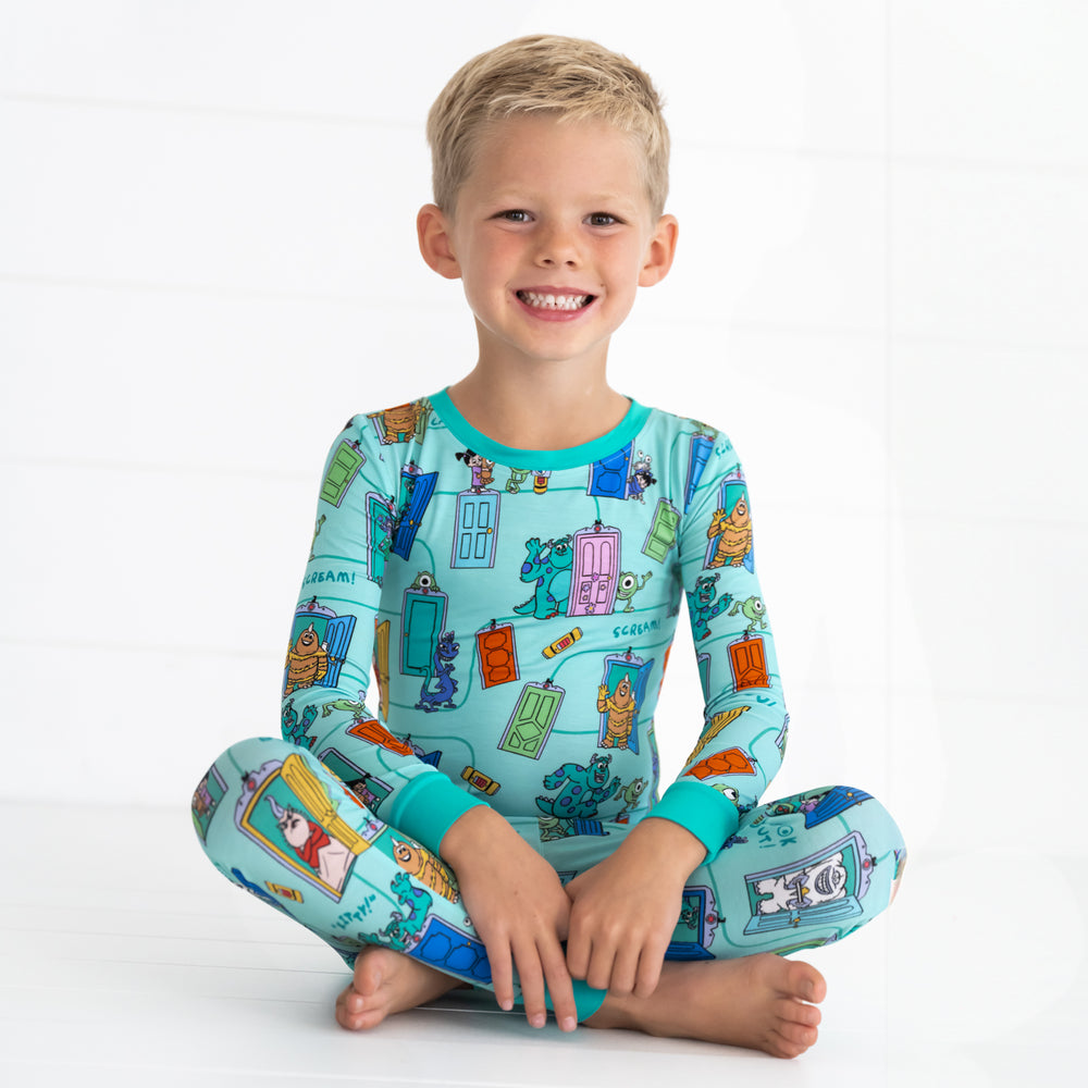 Smiling boy sitting down while wearing the Disney Monsters, Inc. Scream Team Two-Piece Pajama Set