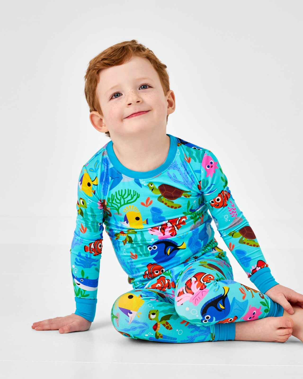 Sitting boy wearing the Pixar Nemo's Reef Two-Piece Pajama Set