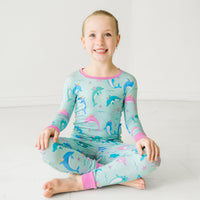 Child sitting on the ground wearing a Dolphin Dance two-piece pajama set