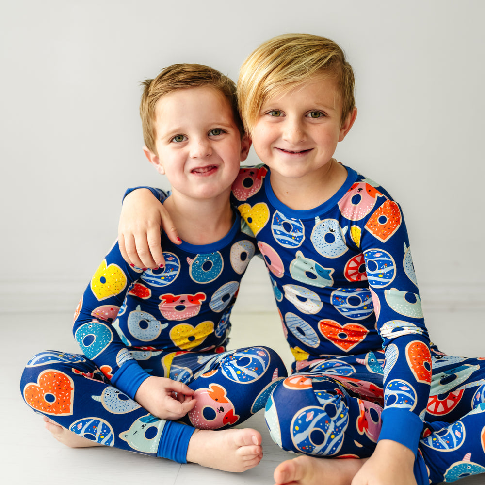 two children sitting and cuddling wearing matching Blue Donuts two piece pajama set
