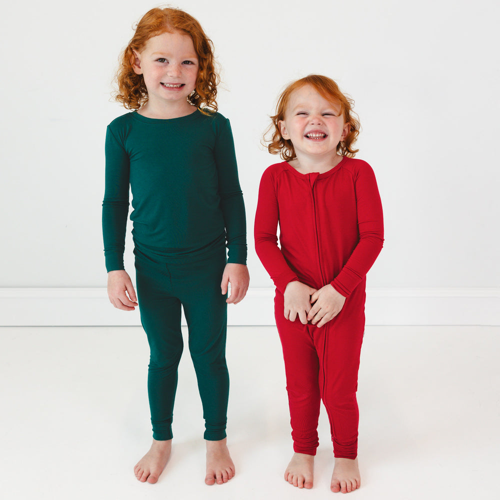 Child on the left is in the Emerald Two-Piece Pajama Set and child on the right is in the Holiday Red Zippy