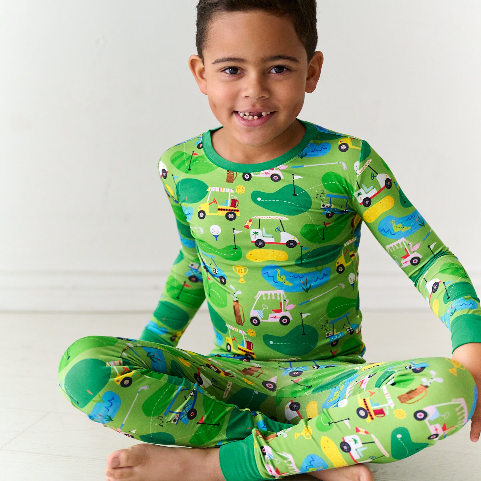 Child sitting on the ground wearing a Fairway Fun two-piece pajama set