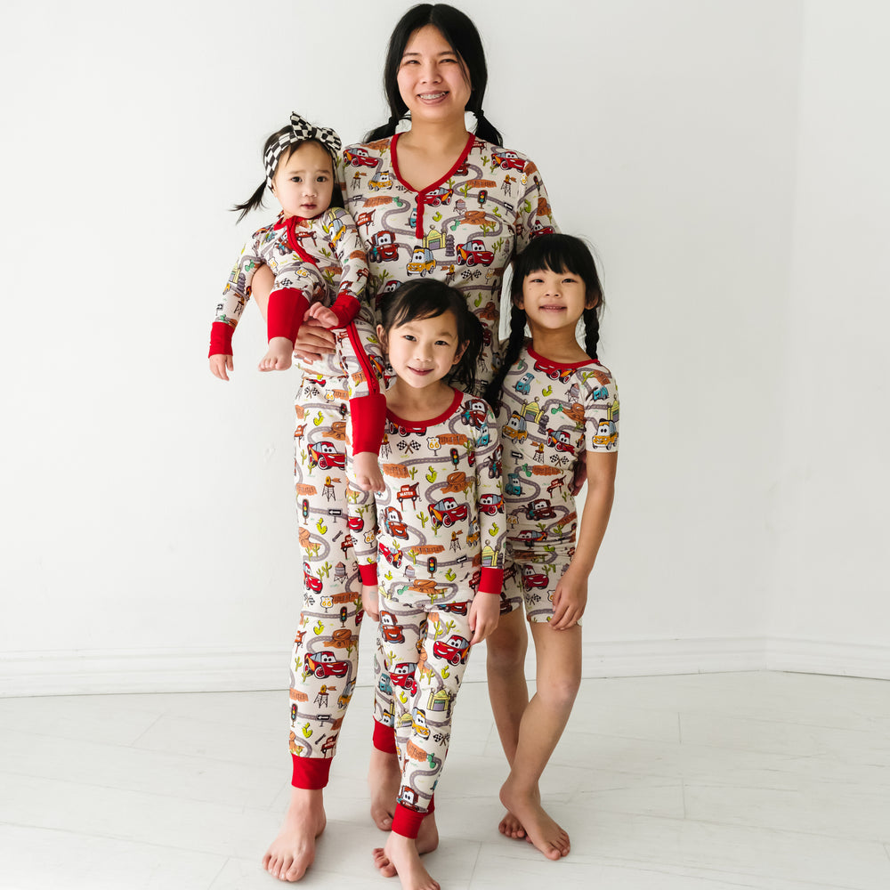 Mother and her three children wearing matching Radiator Springs pajamas. Mom is wearing Radiator Springs women's pajama top and matching women's pajama pants. Kids are wearing Radiator Springs pjs in two piece and zippy styles