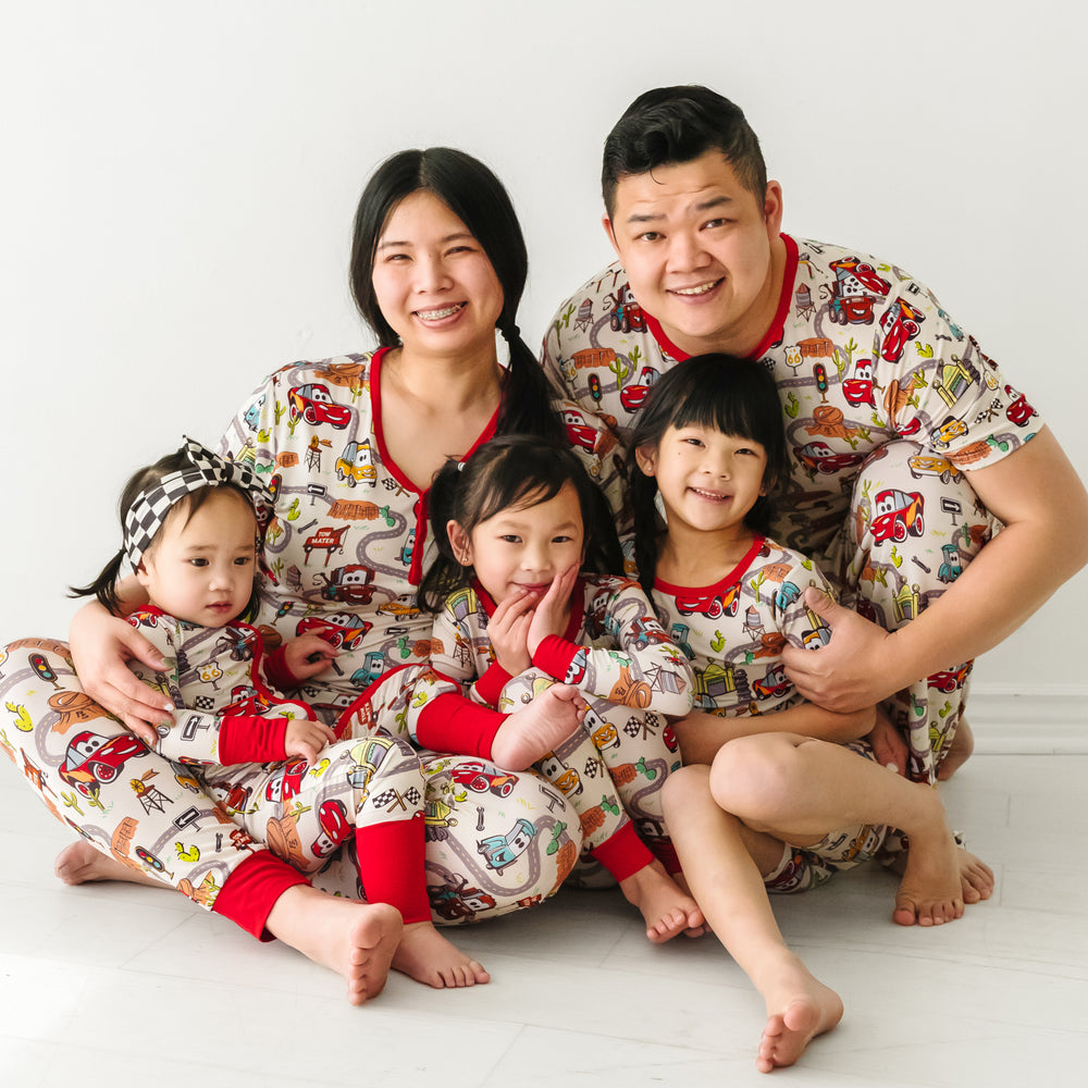Family of five wearing matching Radiator Springs pajamas. Mom is wearing Radiator Springs women's pajama top and matching women's pajama pants. Dad is wearing men's Radiator Springs pajama top and matching men's pj pants. Kids are wearing Radiator Springs pjs in two piece and zippy styles