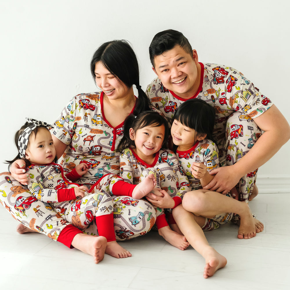 Family of five wearing matching Radiator Springs pajamas. Mom is wearing Radiator Springs women's pajama top and matching women's pajama pants. Dad is wearing men's Radiator Springs pajama top and matching men's pj pants. Kids are wearing Radiator Springs pjs in two piece and zippy styles